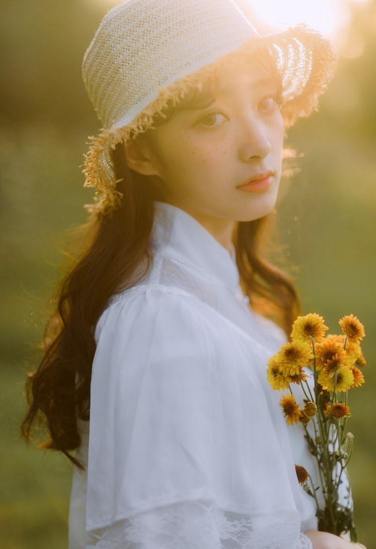 文藝美女潔白長裙濃密卷發手捧鮮花叢林寫真圖片