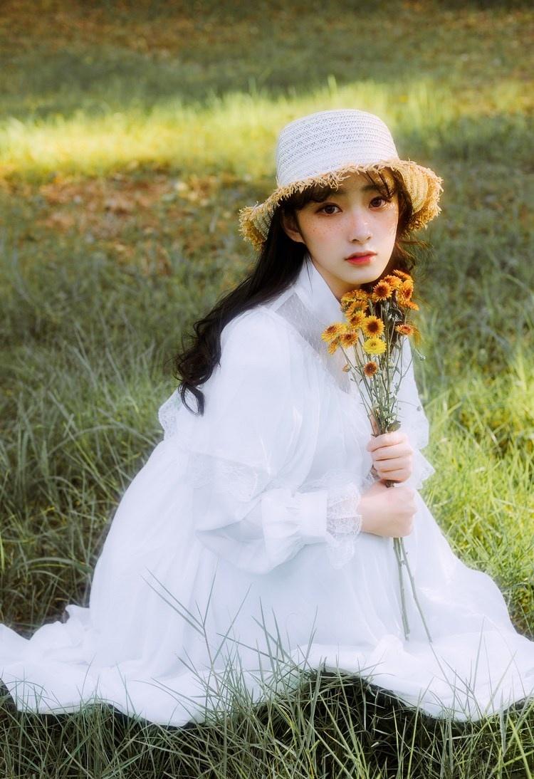 文藝美女潔白長裙濃密卷發手捧鮮花叢林寫真圖片