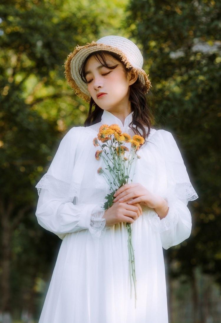 文藝美女潔白長裙濃密卷發手捧鮮花叢林寫真圖片