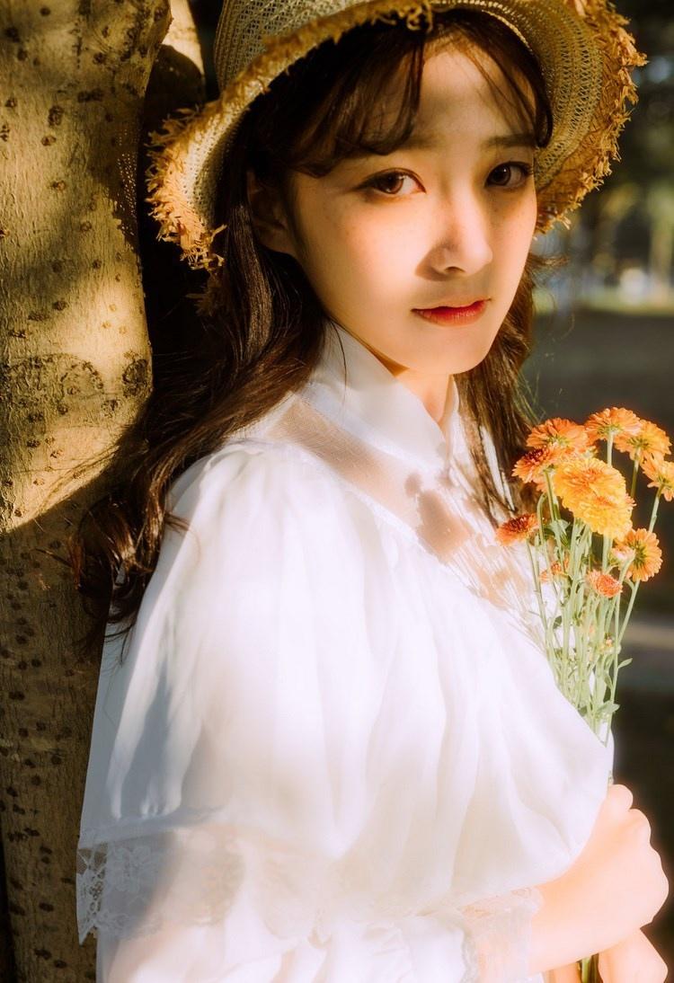 文藝美女潔白長裙濃密卷發手捧鮮花叢林寫真圖片