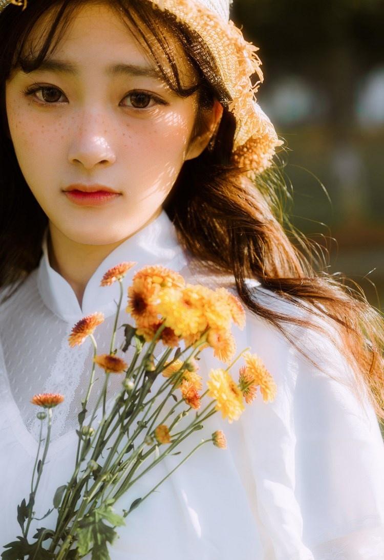 文藝美女潔白長裙濃密卷發手捧鮮花叢林寫真圖片
