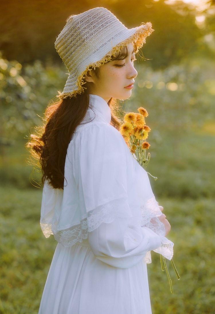 文藝美女潔白長裙濃密卷發手捧鮮花叢林寫真圖片