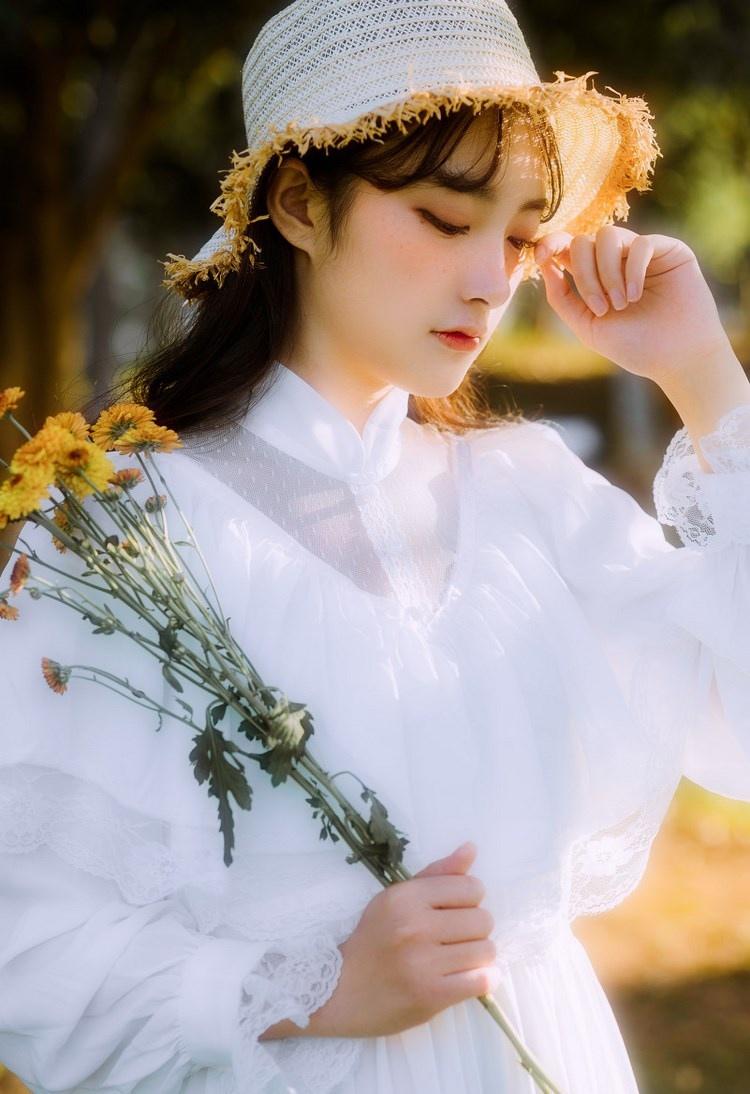 文藝美女潔白長裙濃密卷發手捧鮮花叢林寫真圖片