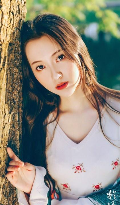 大樹下清純靈動美女手捧蘋果纖細身形圖片