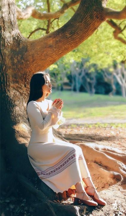 大樹下清純靈動美女手捧蘋果纖細身形圖片