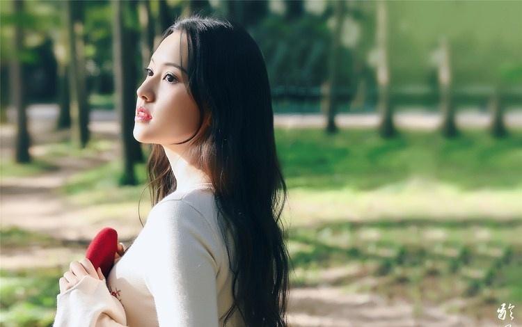 大樹下清純靈動美女手捧蘋果纖細身形圖片