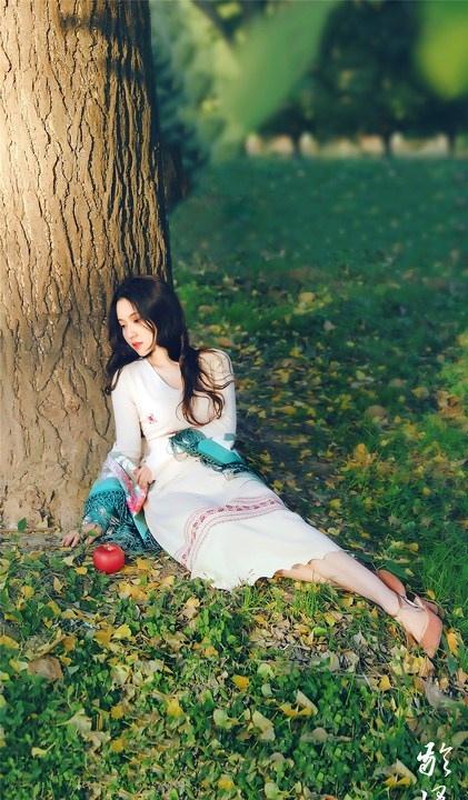 大樹下清純靈動美女手捧蘋果纖細身形圖片