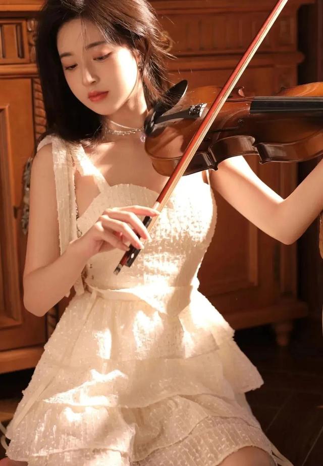 穿著可甜可鹽白色吊帶蛋糕裙的小提琴女孩